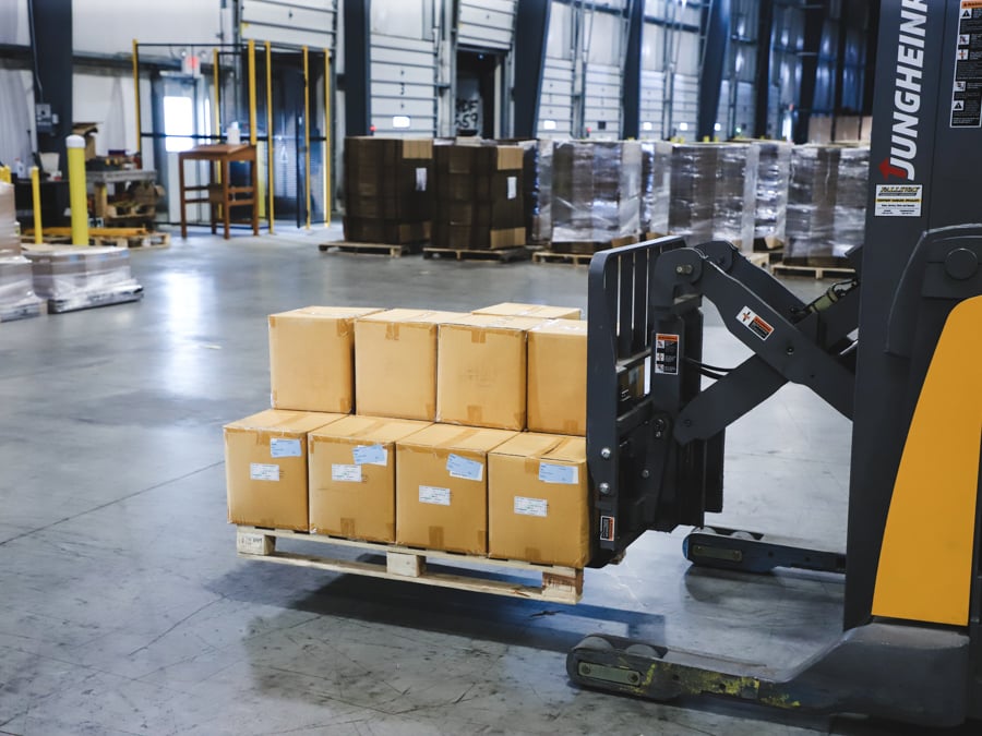 a yellow forklift moving a palette of products across a warehouse