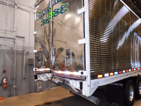 Rear door of a semi-truck trailer that was dented and damaged from an accident